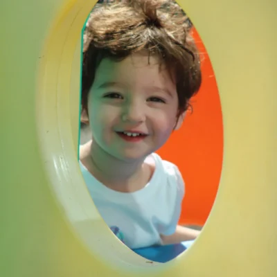 rock-spring-childrens-center9 Smiling child peeking through a round window in a play structure